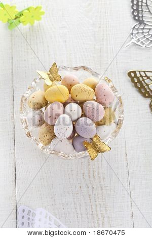 chocolate speckled eggs in bowl with batterfly on old white table