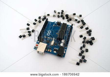 Arduino and around transistors lined up on a white background