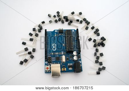 Arduino and around transistors lined up on a white background