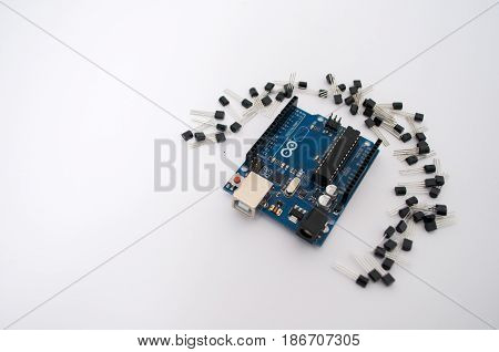 Arduino and around transistors lined up on a white background