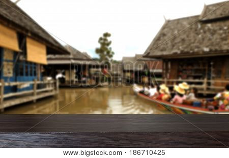 Wooden board empty table top on of blurred background,Perspective drak wood table over blur in floating market background can be used mock up for montage products display or design key visual layout.