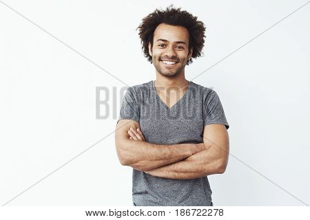Portrait of stong and handsome african man looking at camera posing with crossed arms over white background. Confident entrepreneur or student. Copy space.