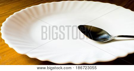 A Silver Spoon Lying on a White,Round Plate