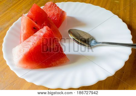 Delicious Watermelon Slices on a White plate with a Metal Spoon