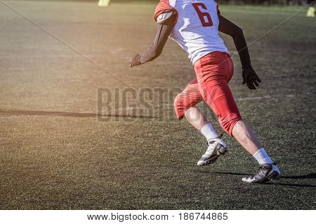 Unrecognizable football player running on the green grass court