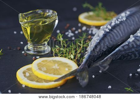 Fresh raw fish mackerel and ingredients for cooking on a dark background in a rustic style. Top view with copy space