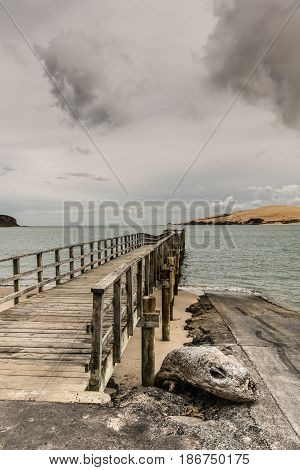 Bay of Islands New Zealand - March 7 2017: Exit to Tasman Sea from Hokianga Harbour shows large dune and pier pointing at entrance all under heavy cloudscape because of approaching cyclone.