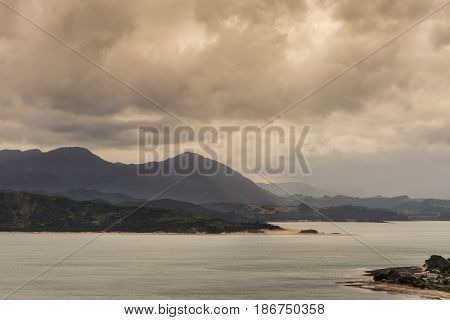 Bay of Islands New Zealand - March 7 2017: Mountains opposite Opononi town on shore of Hokianga Harbour. All under heavy cloudscape because of approaching cyclone.