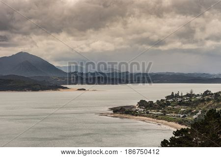 Bay of Islands New Zealand - March 7 2017: Opononi town and mountains on Hokianga Harbour. All under heavy cloudscape because of approaching cyclone.