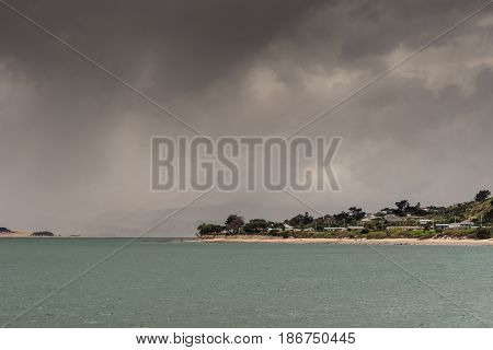 Bay of Islands New Zealand - March 7 2017: Opononi town on shore of Hokianga Harbour. Hokianga River and town under heavy cloudscape because of approaching cyclone.