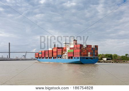 Fully loaded cargo container ship approaching the Talmadge Memorial Bridge as it enters Port of Savannah in Georgia. Copy space in sky if needed.