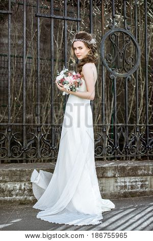 Brunette bride in fashion white wedding dress with makeup. Wedding day of bride in bridal gown. Beauty woman and bouquet. Fashion brunette model outdoors. Portrait beauty model in white bridal dress