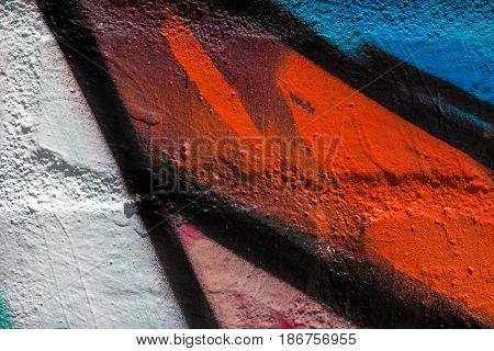Close up of white, red, blue, pink and black paint on a brick wall