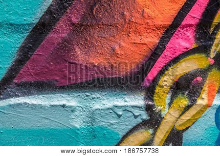 Close up of red, blue, pink, orange, yellow and black painted brick will with a chain