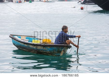 Aberdeen Hong Kong - March 12 2017: unidentified Tanka man in a canoe in the harbour of Aberdeen. Tanka people are boat people an ethnic subgroup in Southern China living on boats in the harbour