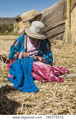 Uros Floating Islands Titicaca Peru - 30 July 2011: Unrecognizable woman in national costume of Indian Uros is embroidering a decorative pillow