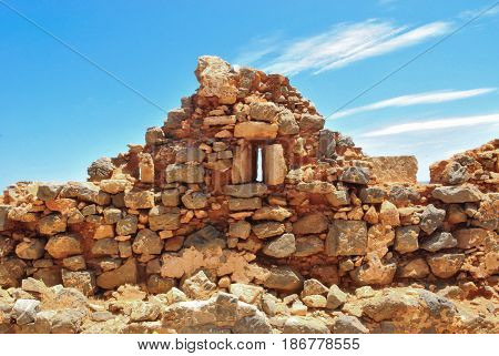 Part of a fortress wall of destroyed Venetian fort of Gramvousa of Crete on blue sky with clouds background