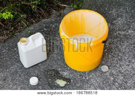 paint bucket yellow and a gallon on the cement floo