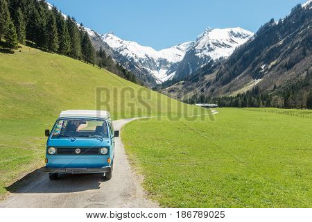OBERSTDORF, BAVARIA, GERMANY - MAY 10, 2017: Vintage blue and white VW Bully camping car driving on mountain valley road in Trettachtal valley, Allgauer Alps.