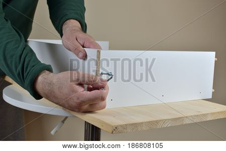 Attaching two particle boards with a screw using Allen key - close-up
