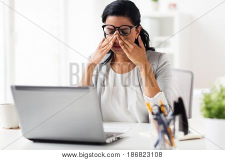 business, overwork, deadline, vision and people concept - tired businesswoman in glasses working at office and rubbing eyes