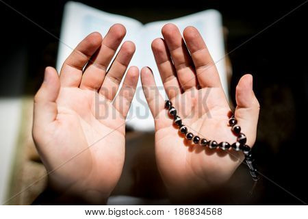 Muslim man hands holding rosary with quraan