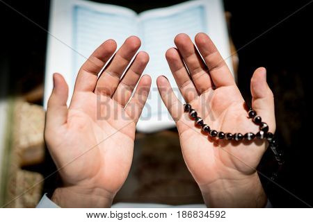 Muslim man hands holding rosary with quraan