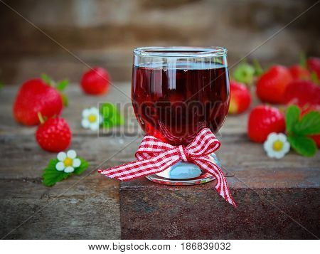 homemade liqueur from strawberries and fresh flowers and berries on a wooden Board