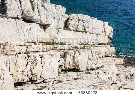 Beautiful white rock ocean coast as geology stone layers going in to the blue sea as background full of bright sunlight on a sunny summer day