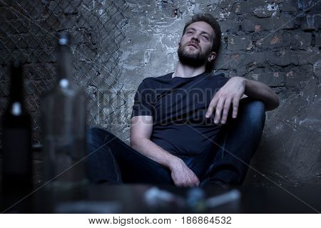 Blurred poisoned reality. Used medical unpacked syringes lying on the table while freak sitting in the background
