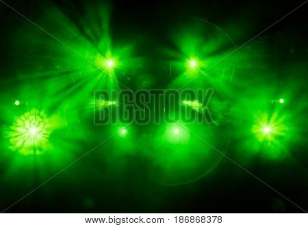 The green light from the spotlights through the smoke in the theatre during the performance. Lighting equipment.