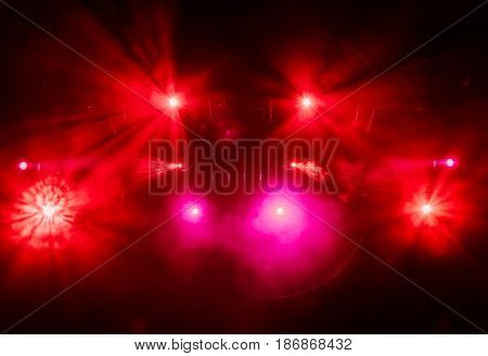 The red light from the spotlights through the smoke at the theater during the performance. Lighting equipment.