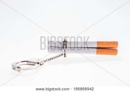 Addition concept with cigarettes and handcuffs on white background