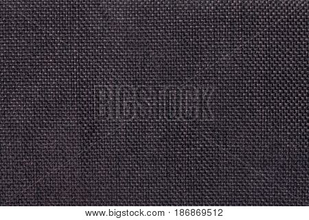Dark brown woolen background of dense woven bagging fabric closeup. Structure of the black cloth with natural texture. Cloth backdrop.