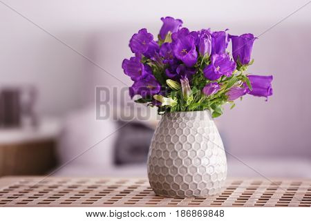 Bouquet of purple bellflowers in vase on wooden table