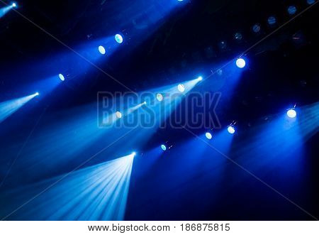 The blue light from the spotlights through the smoke in the theatre during the performance. Lighting equipment.