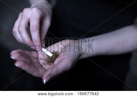 Everyday dangerous addiction. Obsessive young drug addicted woman holding marijuana cigarette while using drug and getting new dose