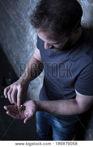 Hiding my real habits. Bearded young dope addicted man holding marijuana cigarette while getting new drug and waiting for dose