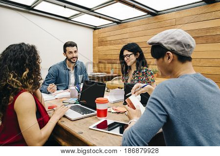 Startup of four multiethnic people discussing joyfully ideas in a modern coworking espace