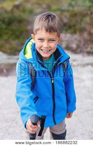 Happy hiking boy with trekking sticks in the mountains. Norway