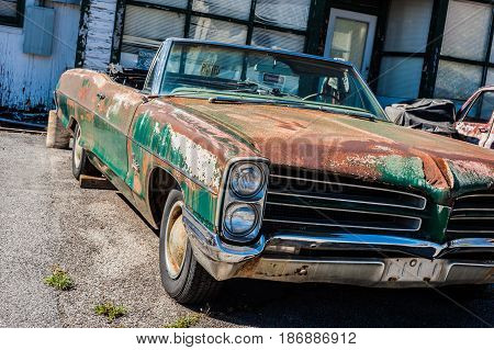 GOSHEN VIRGINIA- APRIL 8 2017: Old car rusting away in front of an abandoned repair shop.