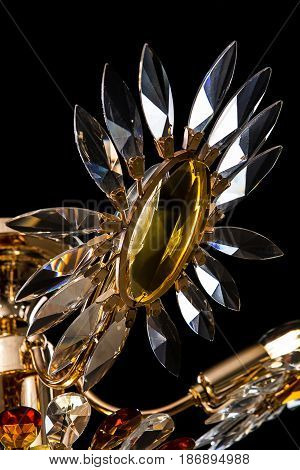 Contemporary gold chandelier isolated on black background. Crystal chandelier decorated amber crystals. close-up
