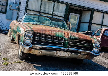 GOSHEN VIRGINIA- APRIL 8 2017: Old car rusting away in front of an abandoned repair shop.