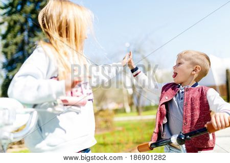 Brother and sister doing handshake in spring park afternoon