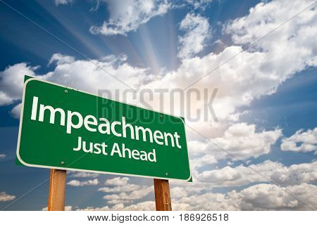 Impeachment Green Road Sign with Dramatic Clouds and Sky