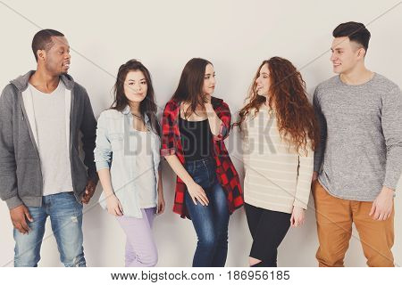 Diverse multiethnic people group. Students in casual outfits standing in line on white studio background