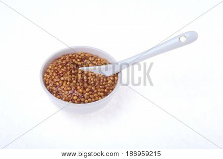 Typical french dijon rough mustard in bowl from isolated on white background.