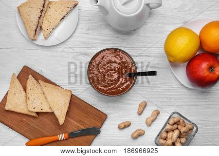 Delicious peanut butter in bowl with different meal on wooden table