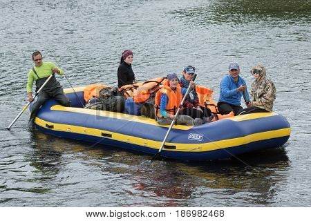 FAST RIVER (BYSTRAYA RIVER) KAMCHATKA PENINSULA RUSSIA - JULY 13 2016: Summer rafting on Kamchatka in gloomy weather: rafting boat with travelers on board floats on waves on muddy mountain river.