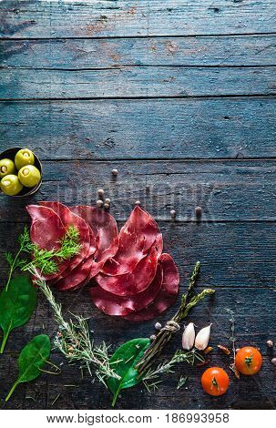 Italian ham prosciutto and salami. Ingredients for bruschetta crostini or sandwich bar. Rustic top view of ingredients. Ham with vegetables and spices